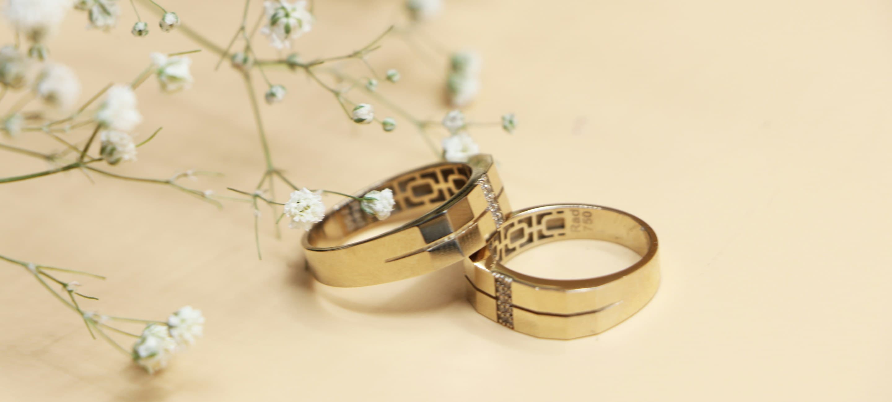 A pair of gold wedding bands beside sprigs of baby's breath