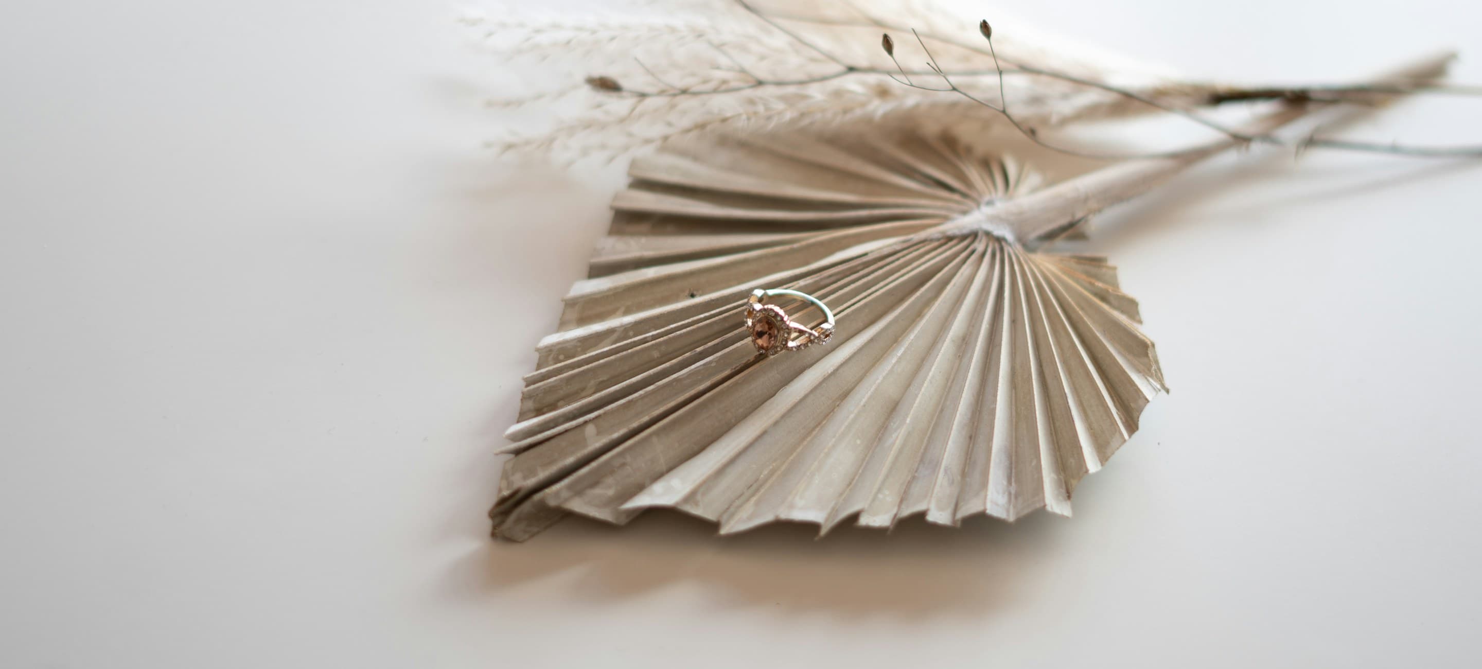 Rose gold solitaire ring resting on a dried palm frond